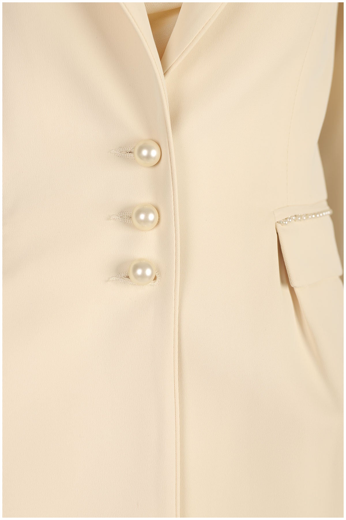 Close-up of a beige coat with pearl buttons on a beige background
