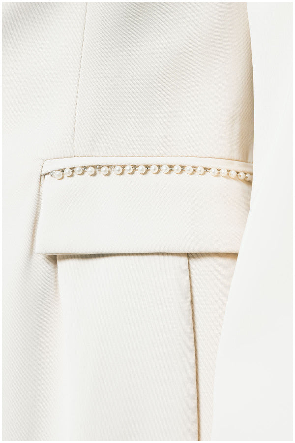 Close-up of a white pearl Luna Fashion House garment with metal trim on a white background