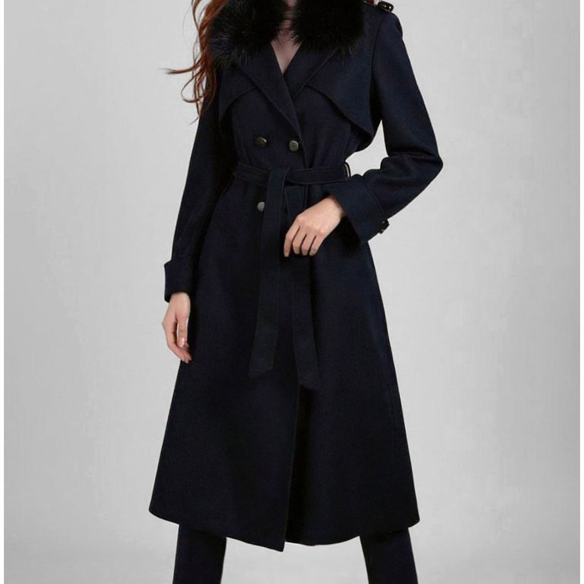 Woman wearing a navy blue coat on a gray background