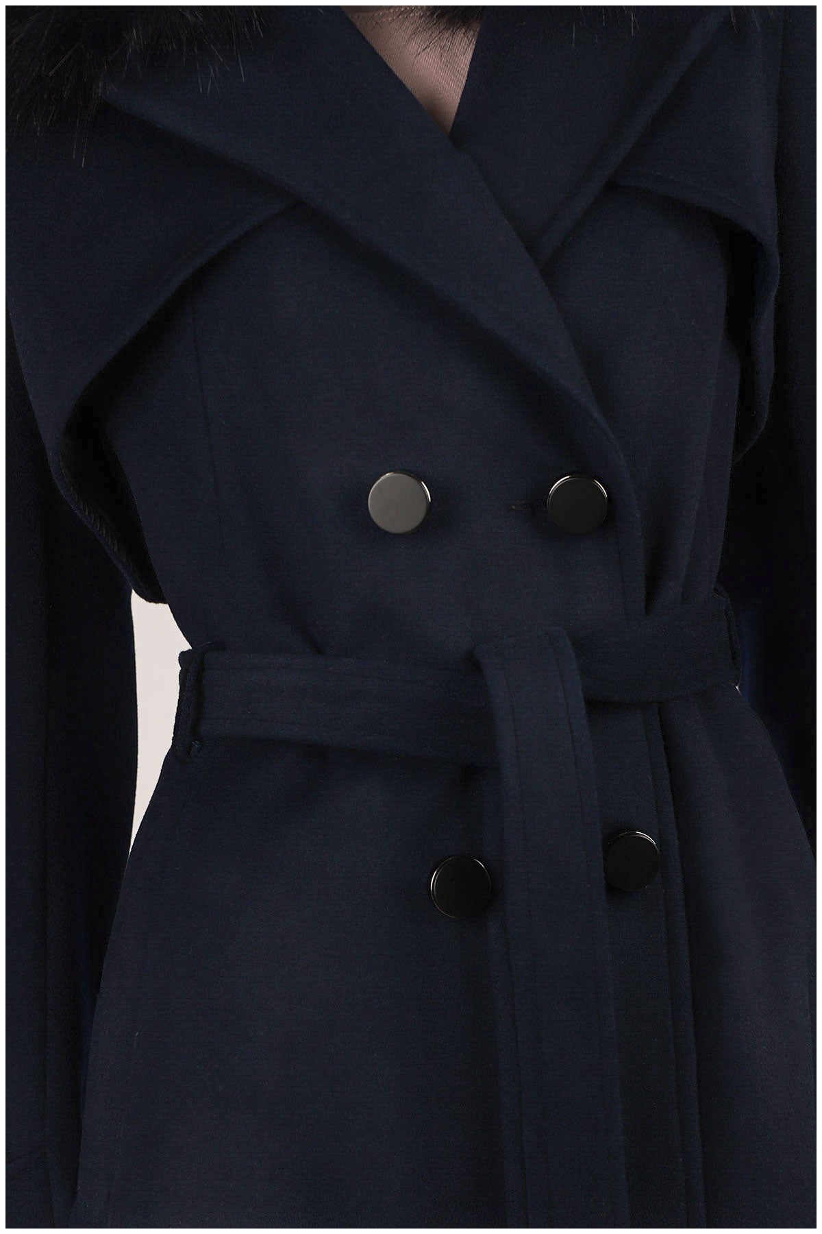 Close-up of a dark blue coat with buttons on a plain background