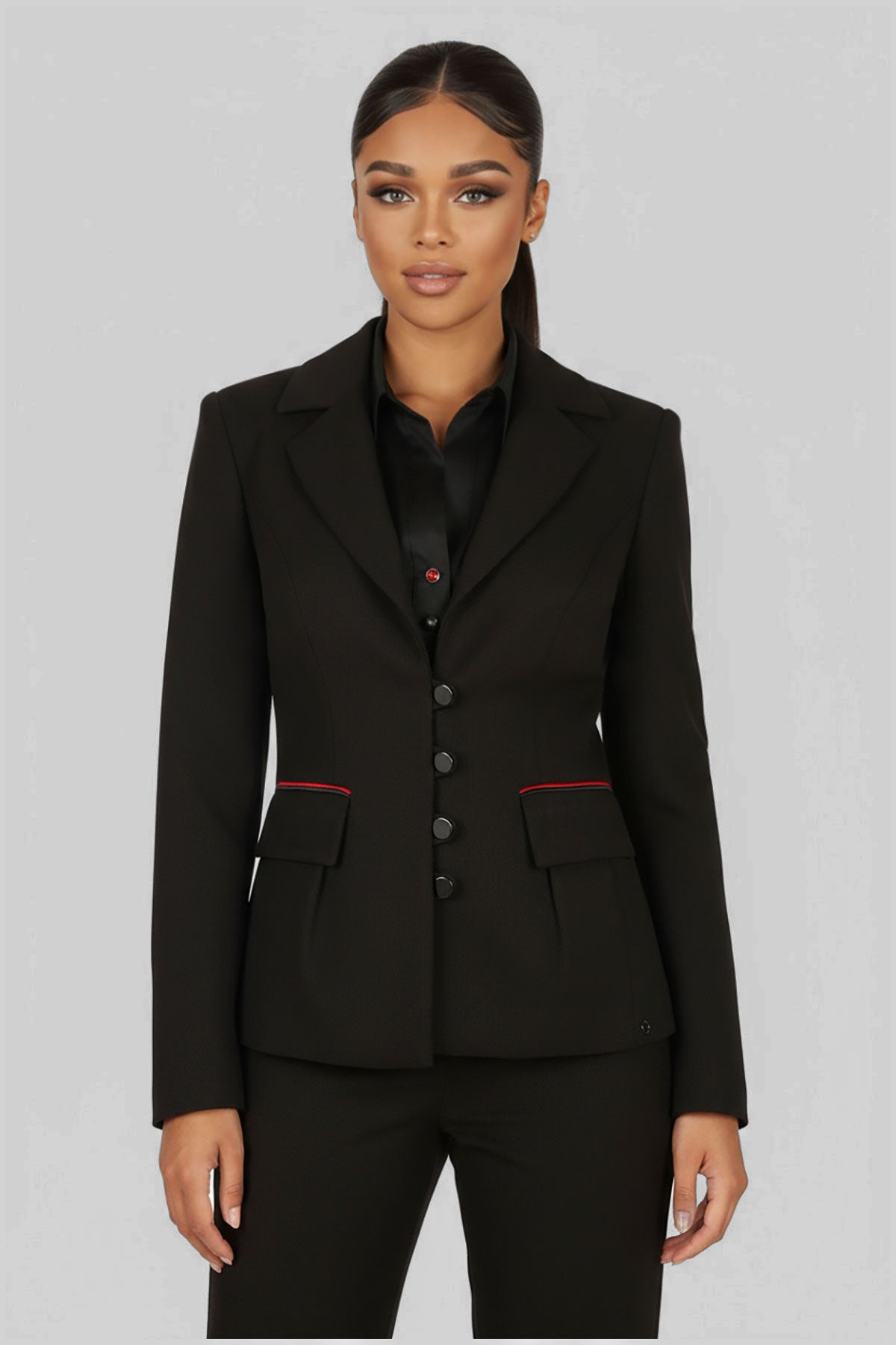 Woman wearing a black suit with red accents on a gray background