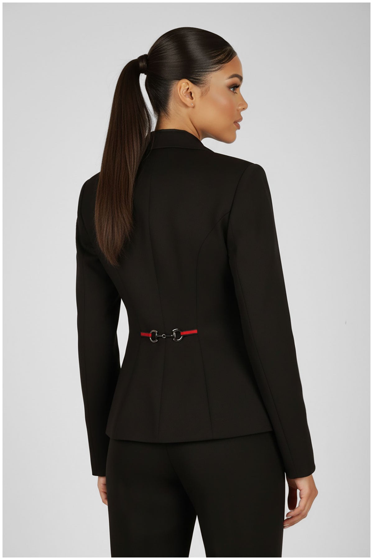 Woman wearing a black suit with a red belt on a gray background