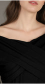Close-up of a person wearing a black Luna Fashion House off-shoulder top with a neutral background