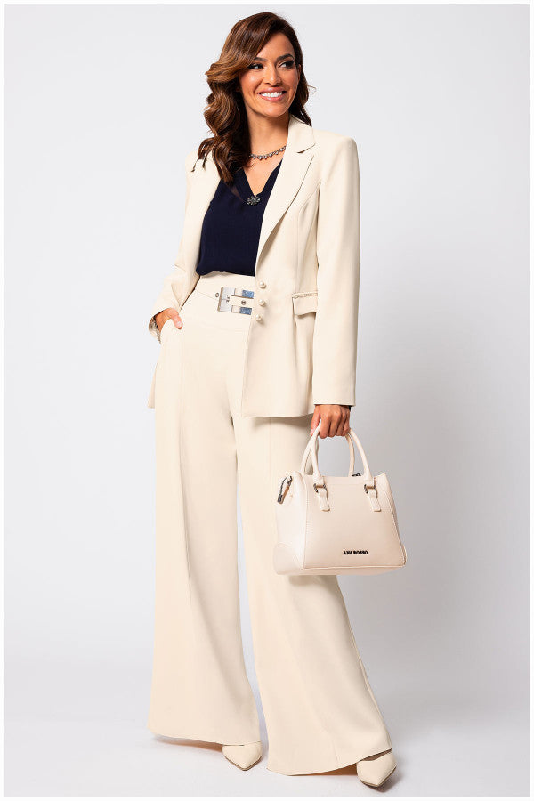 Woman in a beige Luna Fashion House  suit holding a matching handbag against a white background
