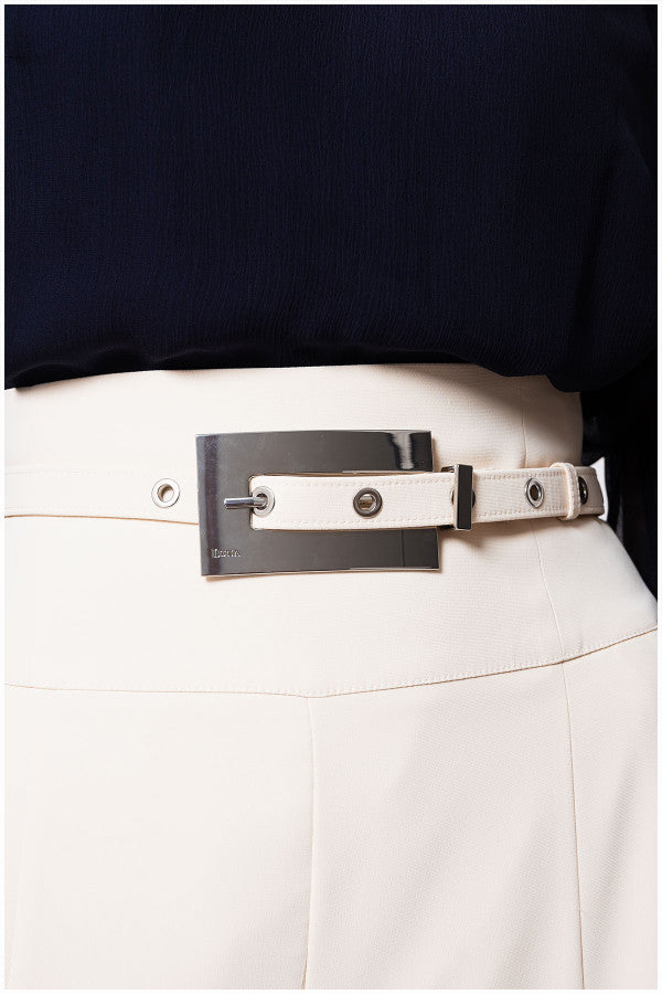 Close-up of a person wearing an ivory Luna Fashion House  belt with a decorative buckle on a plain background