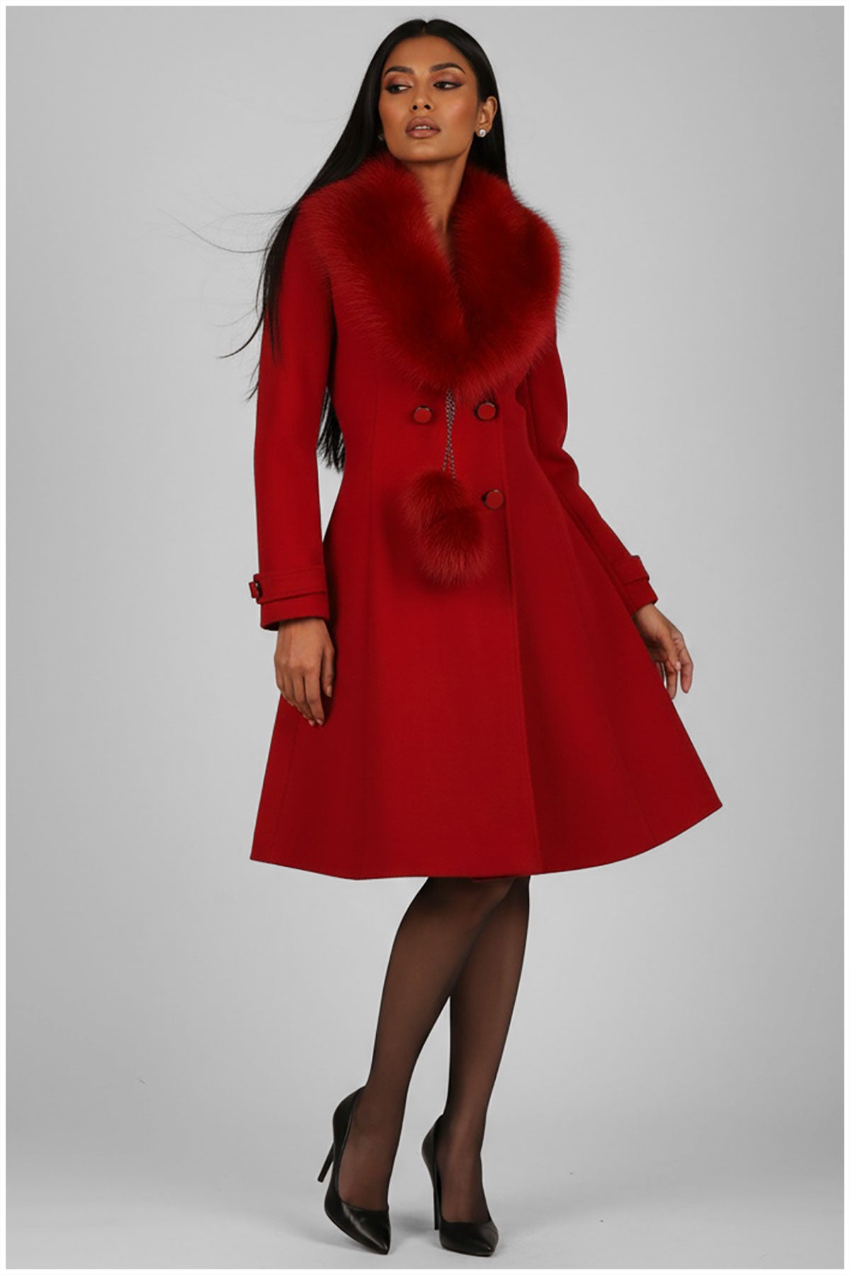 Woman wearing a red coat with fur collar on a gray background