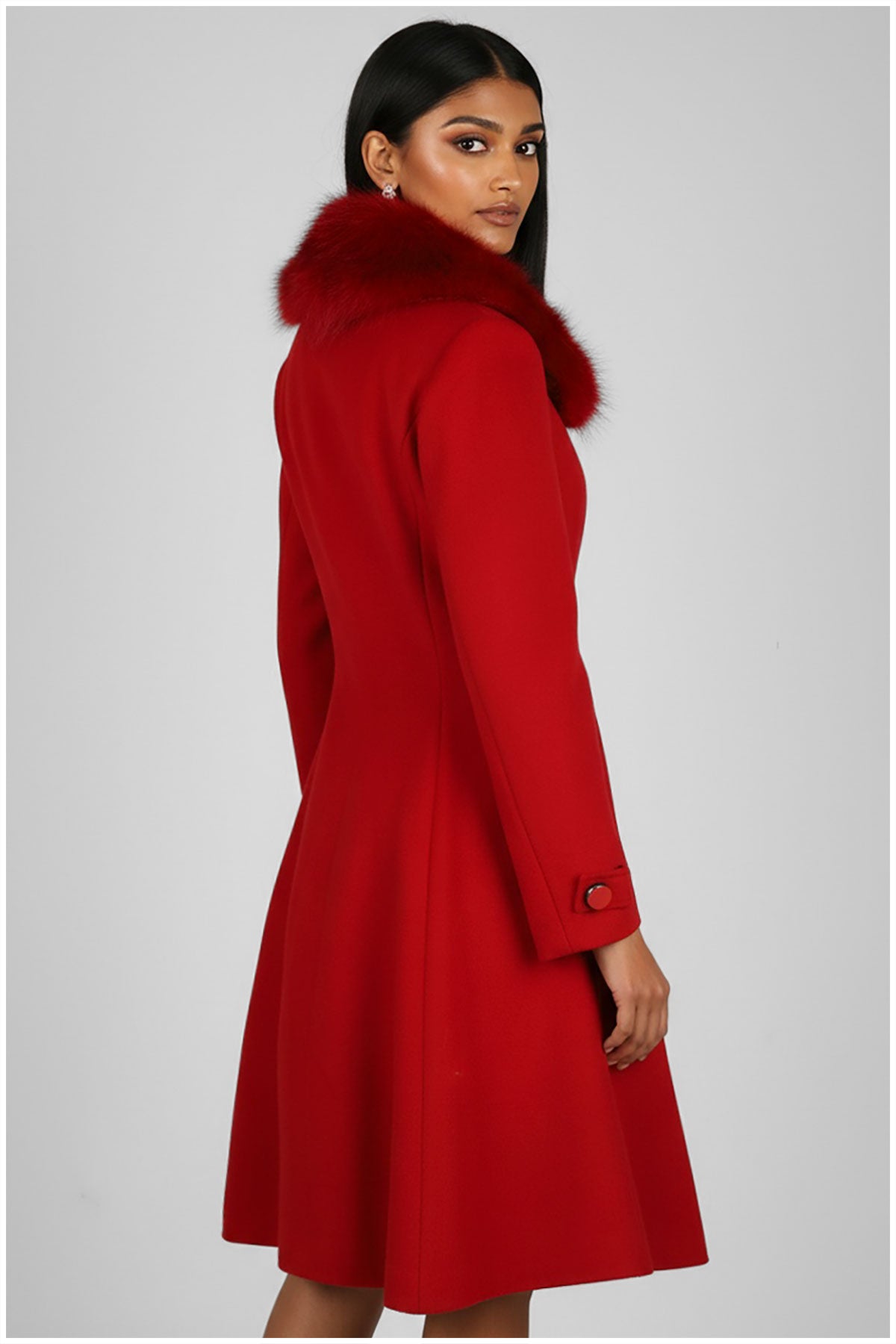 Red coat with fur hood worn by a model on a gray background