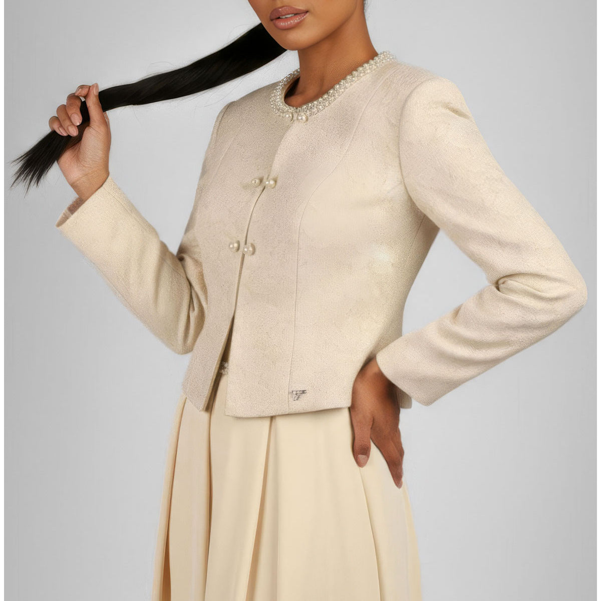 Ivory Jacquard Blazer with Pearl Details, Rhea. Pearls around the round neckline and 2 pearl button closures, worn over an ivory pleated skirt.