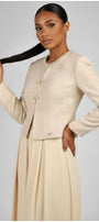 Woman wearing a beige suit with a plain background