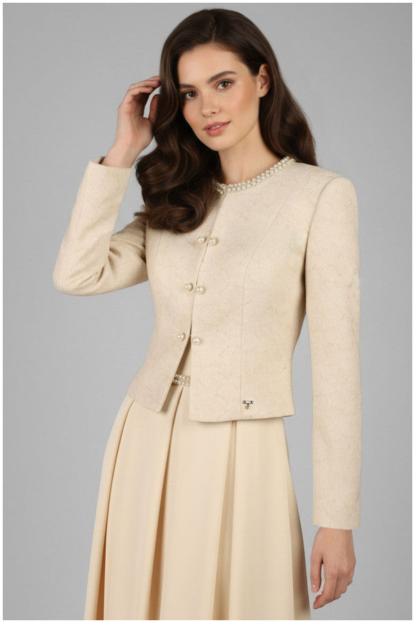 Woman wearing a beige Luna Fashion House suit with a pearl necklace against a gray background