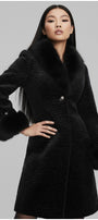 Woman wearing a black coat with fur trim on a gray background