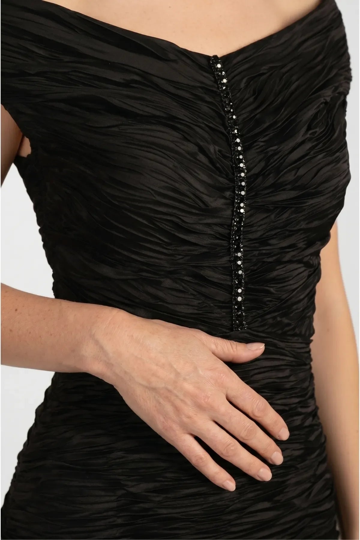Detail of the Lina dress showing the slim vertical crystal trim and the ruched fabric texture across the bodice