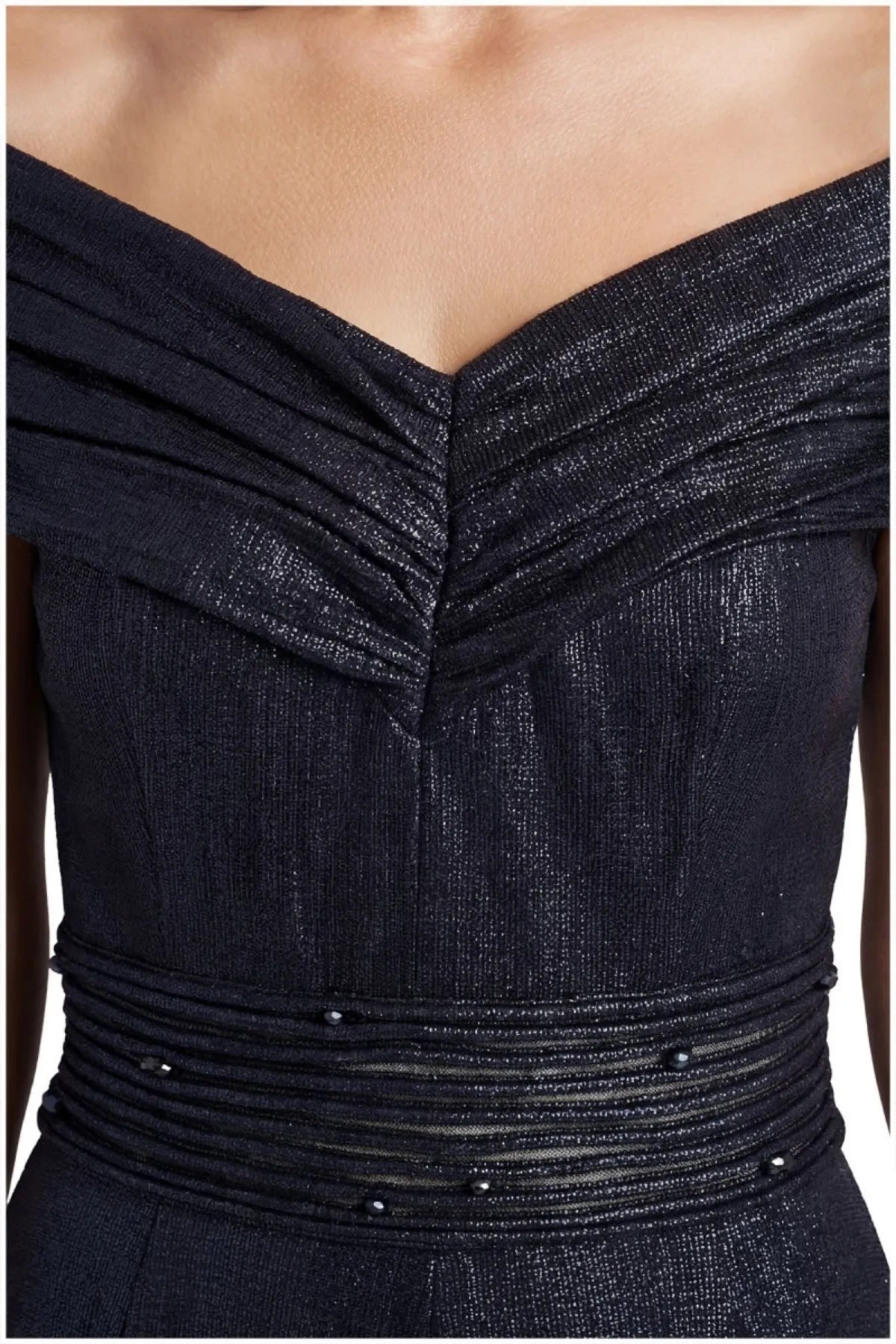 Close view of the navy gown's pleated off-shoulder neckline and beaded semi-sheer waistband