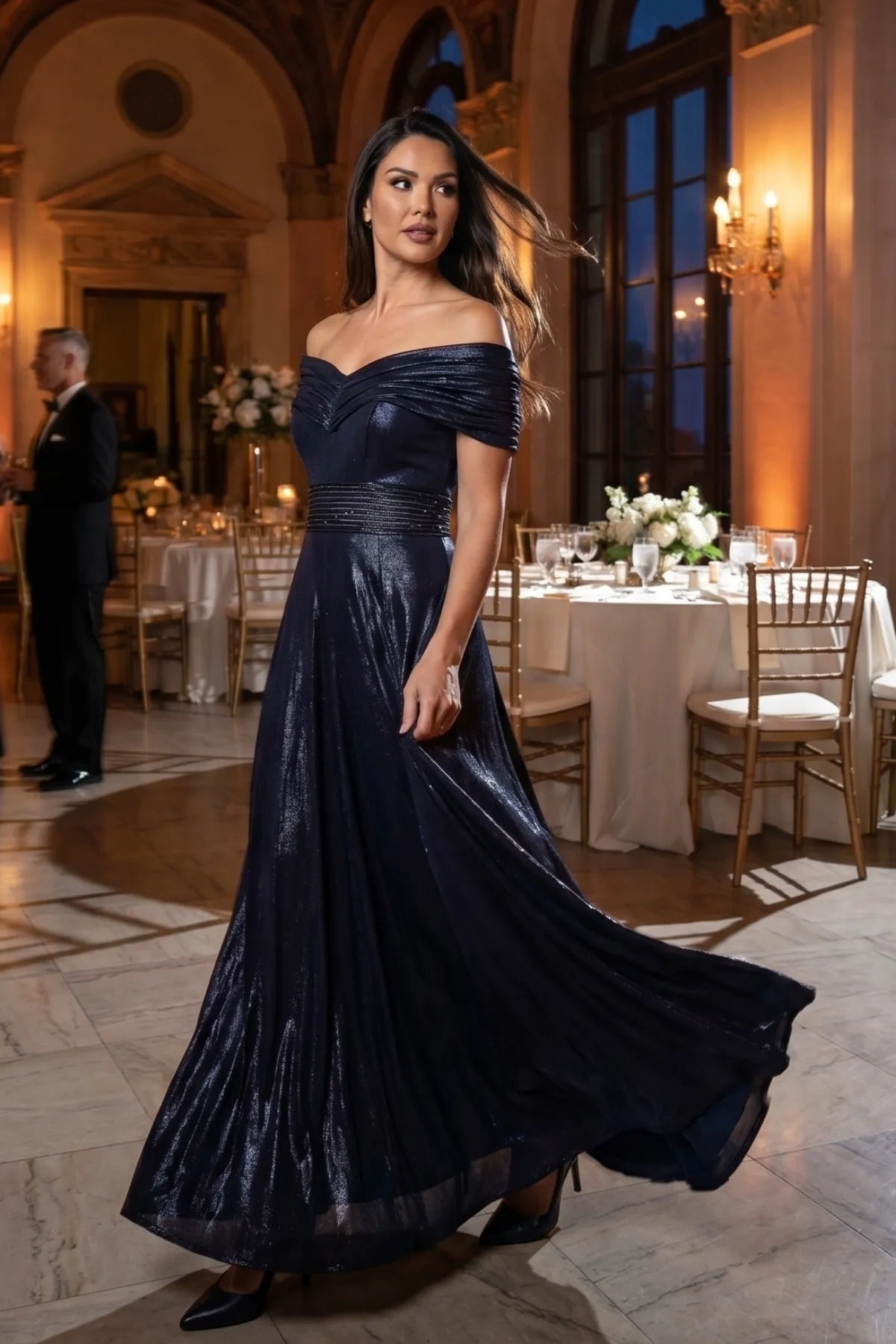 Navy off-shoulder metallic gown with flowing skirt in a candlelit ballroom setting