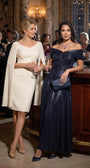 Two guests at an evening event, one in the navy off-shoulder metallic gown at a candlelit bar