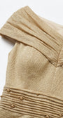 Detail of the champagne gold dress showing pleated off-shoulder neckline construction and shoulder-line draping