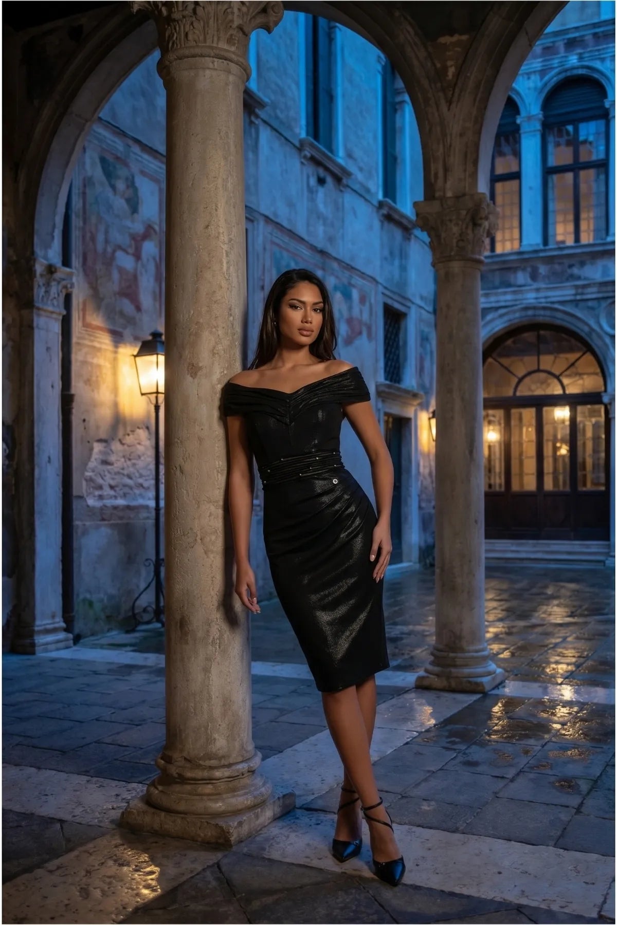 Model wearing the anthracite cocktail dress in a European courtyard at blue hour, framed by stone arches and lanterns.