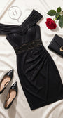 Black cocktail dress styled with patent pumps, a structured clutch, jewelry, and a red rose on ivory satin.