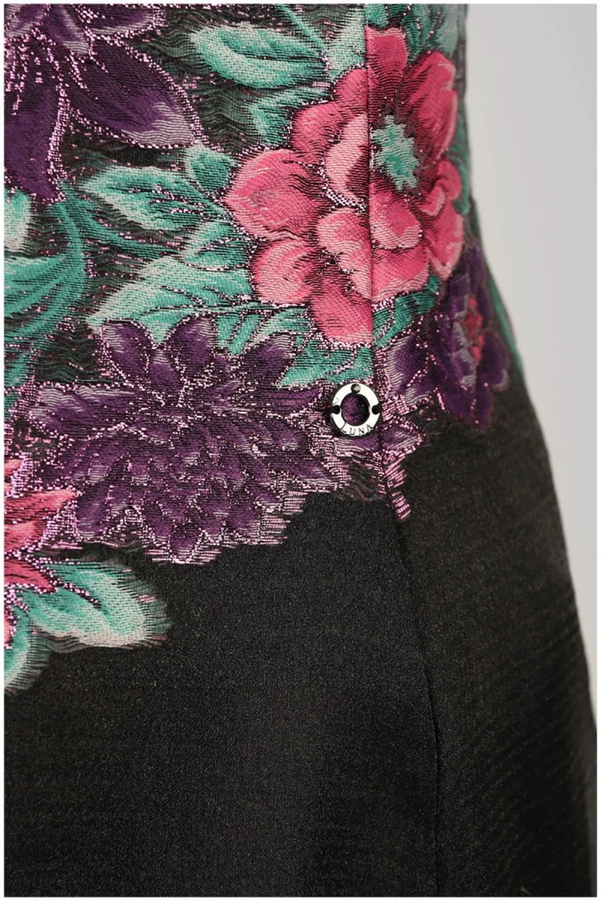 Close-up of Rina floral dress showing cyclamen, purple, and teal embroidery with a small Luna button.