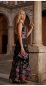 Rina cyclamen floral maxi dress styled with a matching clutch in an elegant European courtyard.