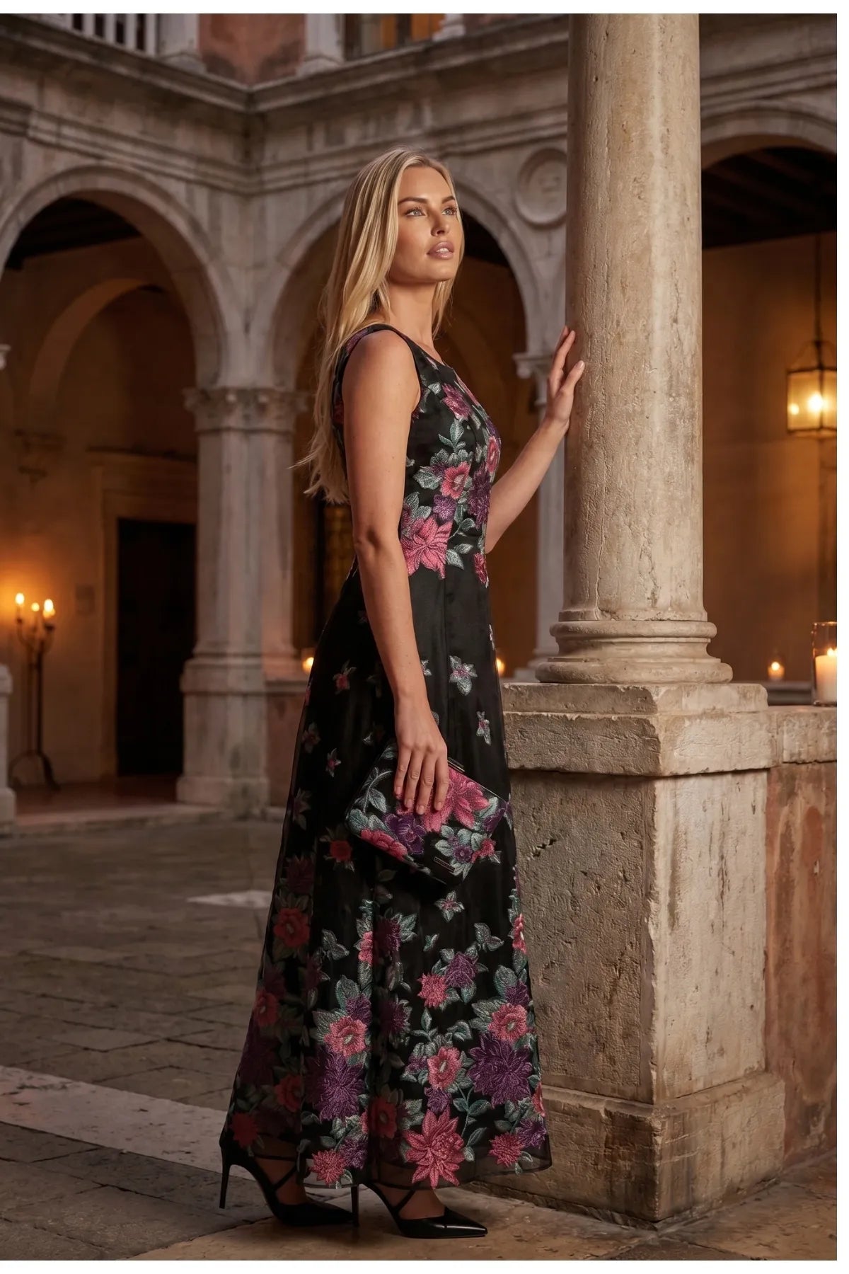 Rina cyclamen floral maxi dress styled with a matching clutch in an elegant European courtyard.