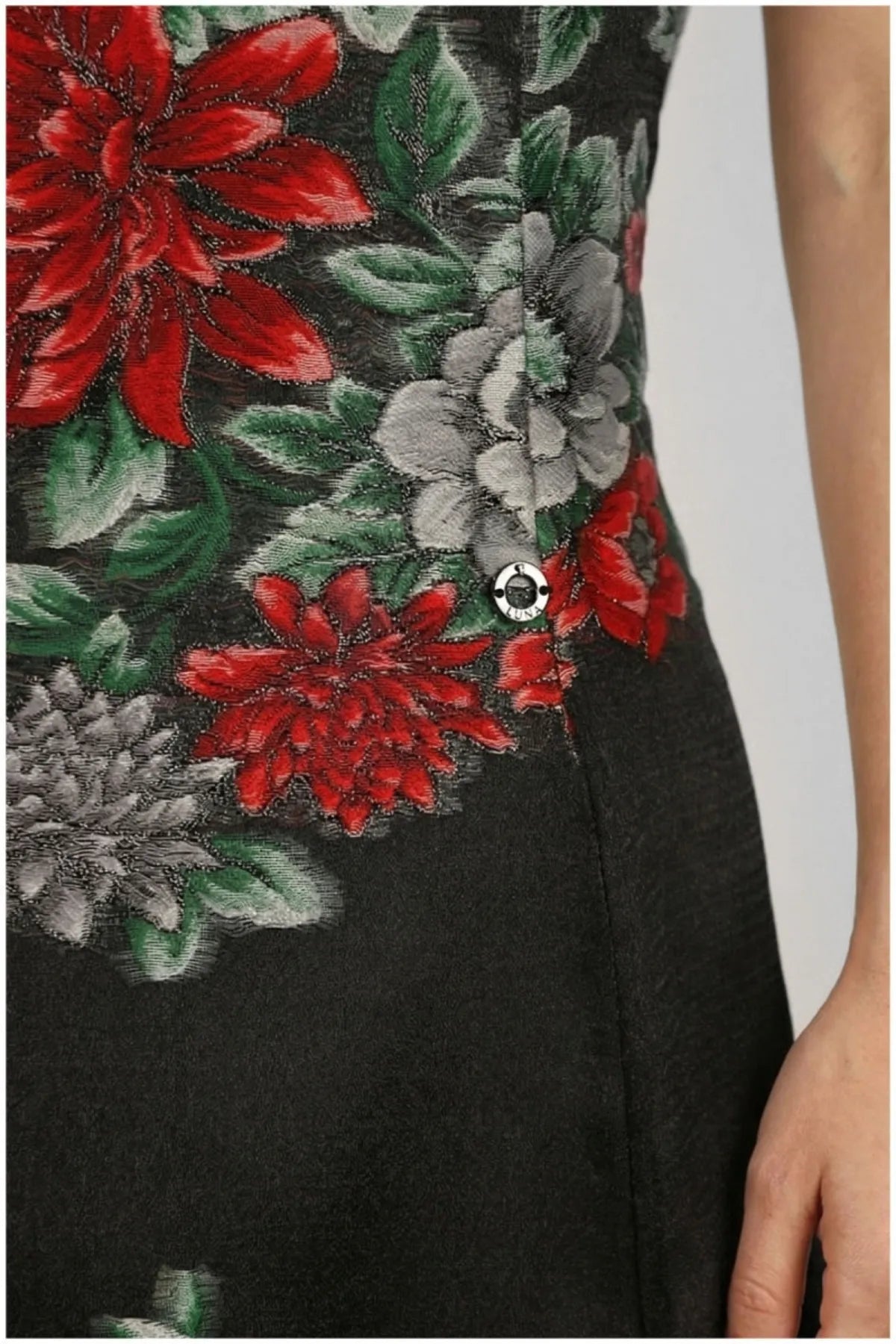 Close-up of red, grey, green floral embroidery on the Rina black dress with Luna button.