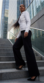 Woman in a white blouse and black pants standing on steps with modern buildings in the background