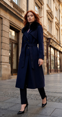 Woman in a navy coat standing on a city street with classical architecture.