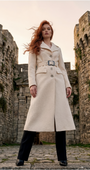 Ivory Belted Midi Coat, Linea. Midi coat. Worn buttoned and belted over black trousers between stone fortress towers at dusk.