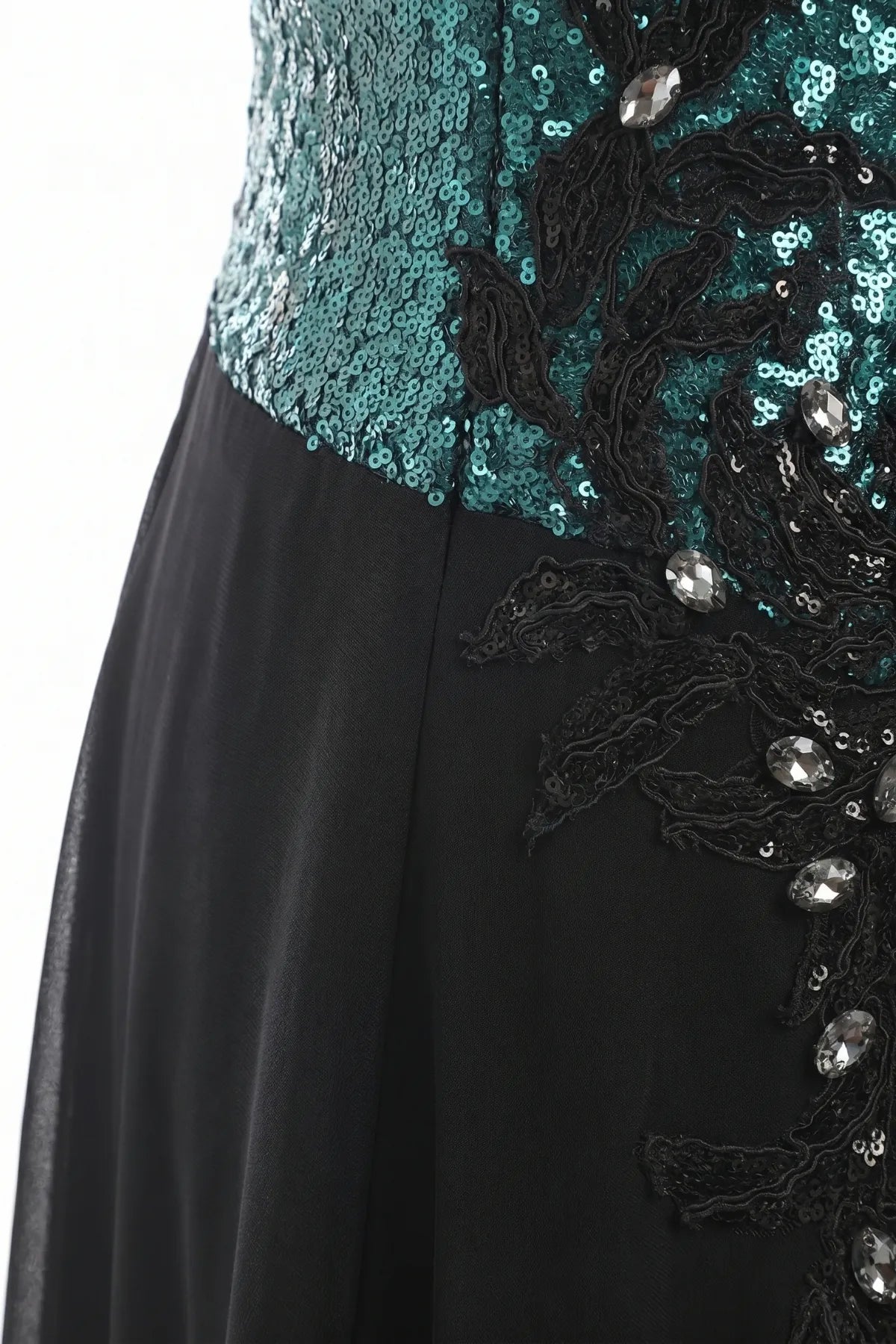 Fabric detail of teal sequins, black floral appliqué, and hand-set crystal accents over sheer black chiffon