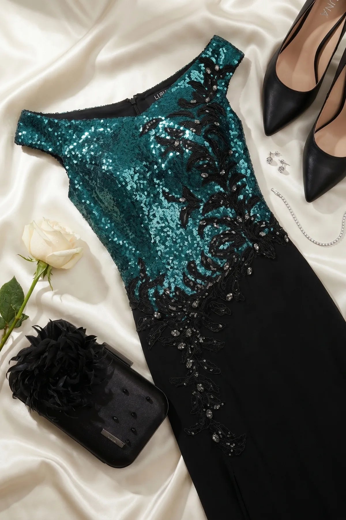 Greta gown styled with black heels, crystal jewelry, a white rose, and a black evening clutch on satin