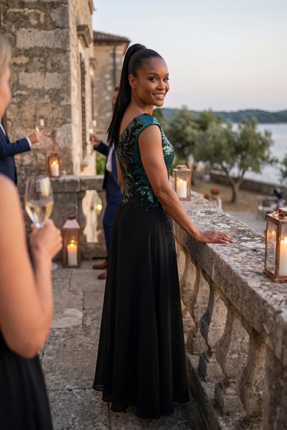 Side view of the Greta gown at a coastal evening reception with stone terrace and candles