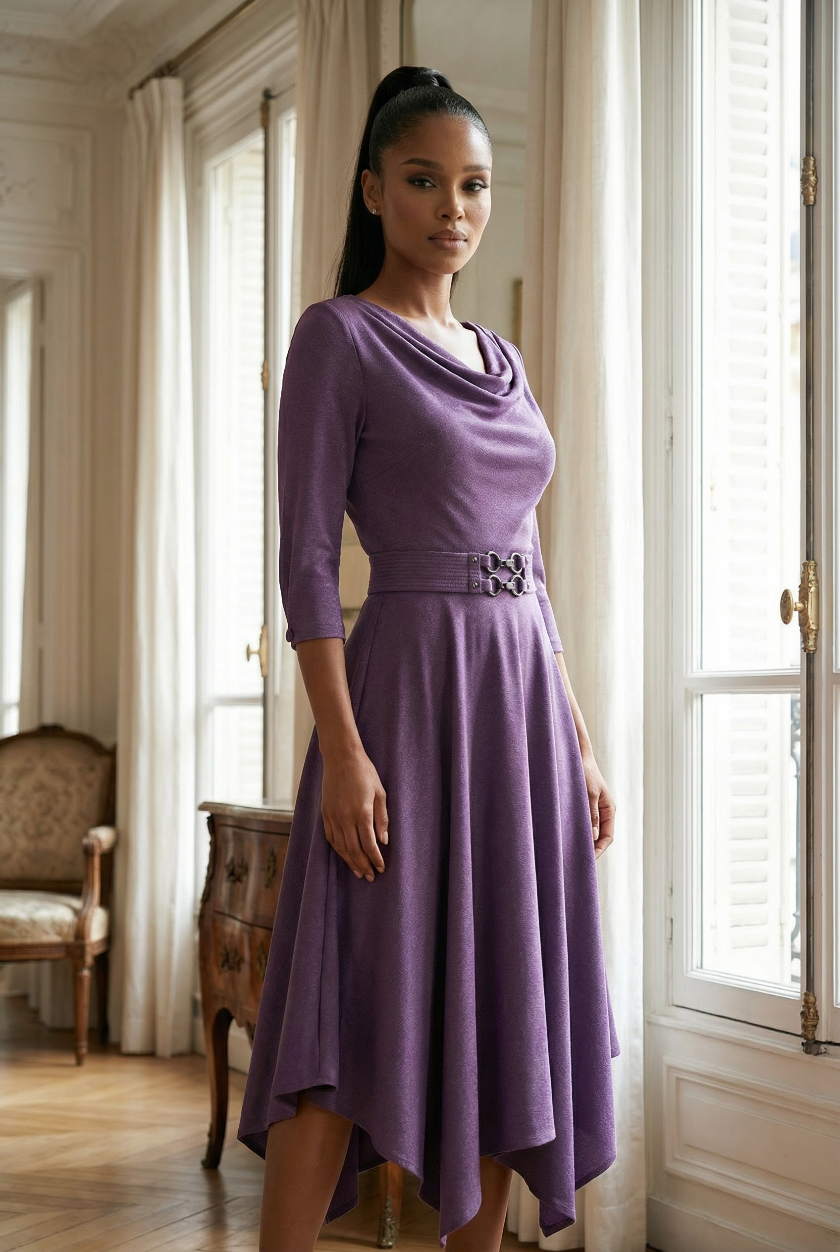 Woman wearing a purple dress standing in a room with large windows and a chair.