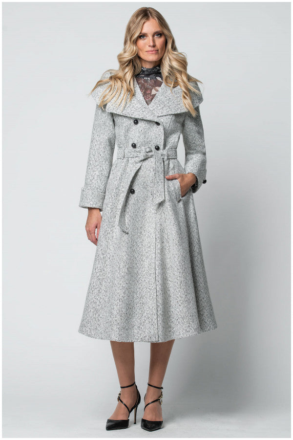 Woman wearing a long gray coat with a belt on a white background
