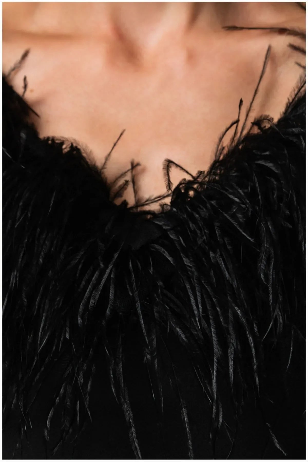 Close-up of the removable black ostrich-feather collar at the V-neckline.