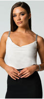Woman wearing an white elegant blouse Dora with jeweled straps paired with a black skirt against a light background