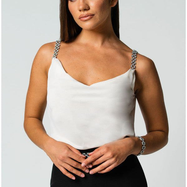 Woman wearing an white elegant blouse Dora with jeweled straps paired with a black skirt against a light background