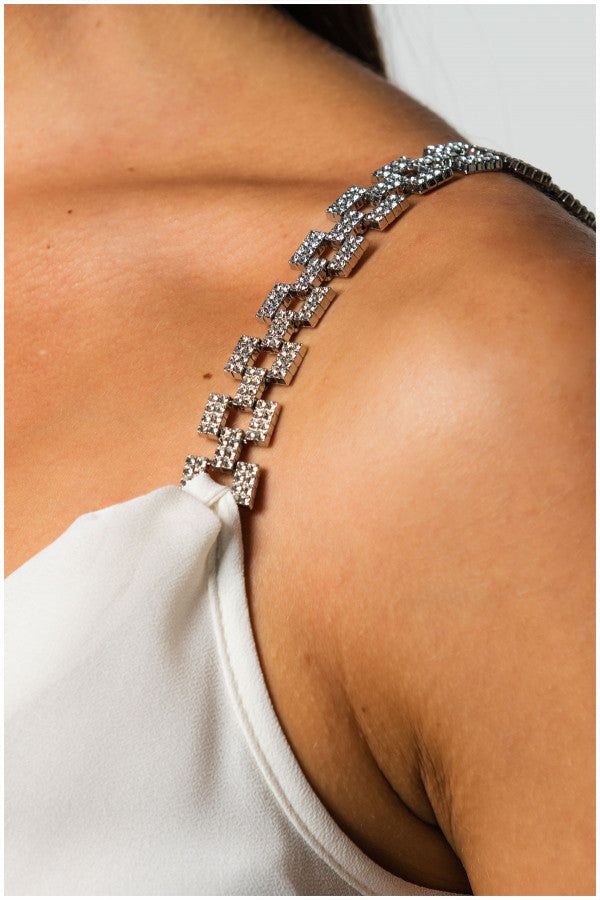 Close-up of white elegant blouse jeweled straps on Dora Blouse showcasing delicate satin fabric and elegant modern design.