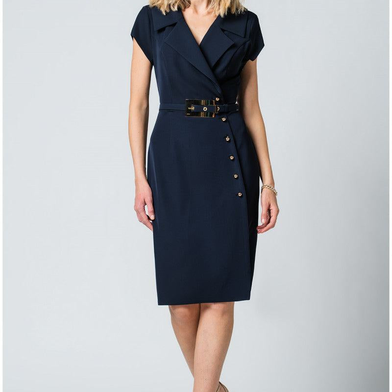 Woman wearing navy wrap dress with structured lapel, metallic buttons, wide belt, and pencil silhouette against white background