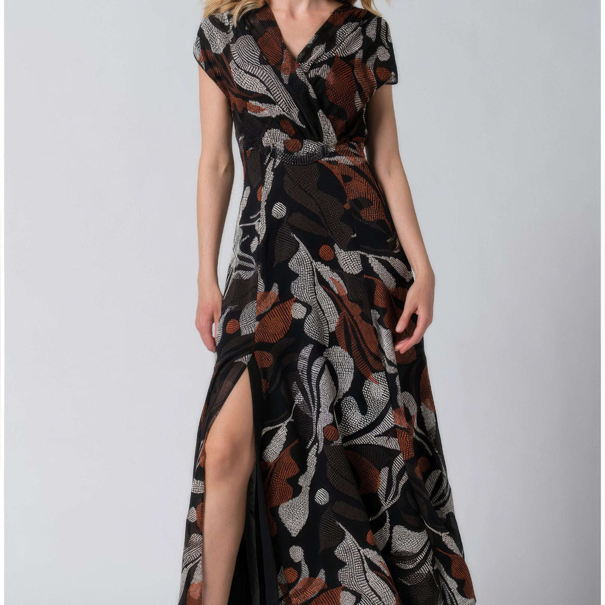 Floral Print Maxi Dress, Lola. Black ground with a rust and cream abstract botanical print, surplice V-neckline, cap sleeves, gathered waist, and a front slit, on model.