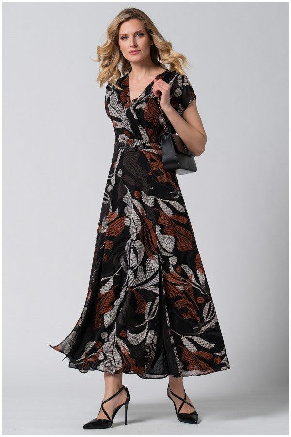 Woman wearing Long Dress Lola with bohemian print, flowing silhouette, and paired with black heels and handbag