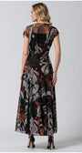 Woman wearing a long black dress with abstract brown and white patterns, featuring a flowing silhouette and sheer sleeves.