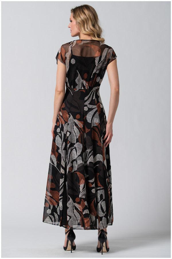 Woman wearing a long black dress with abstract brown and white patterns, featuring a flowing silhouette and sheer sleeves.