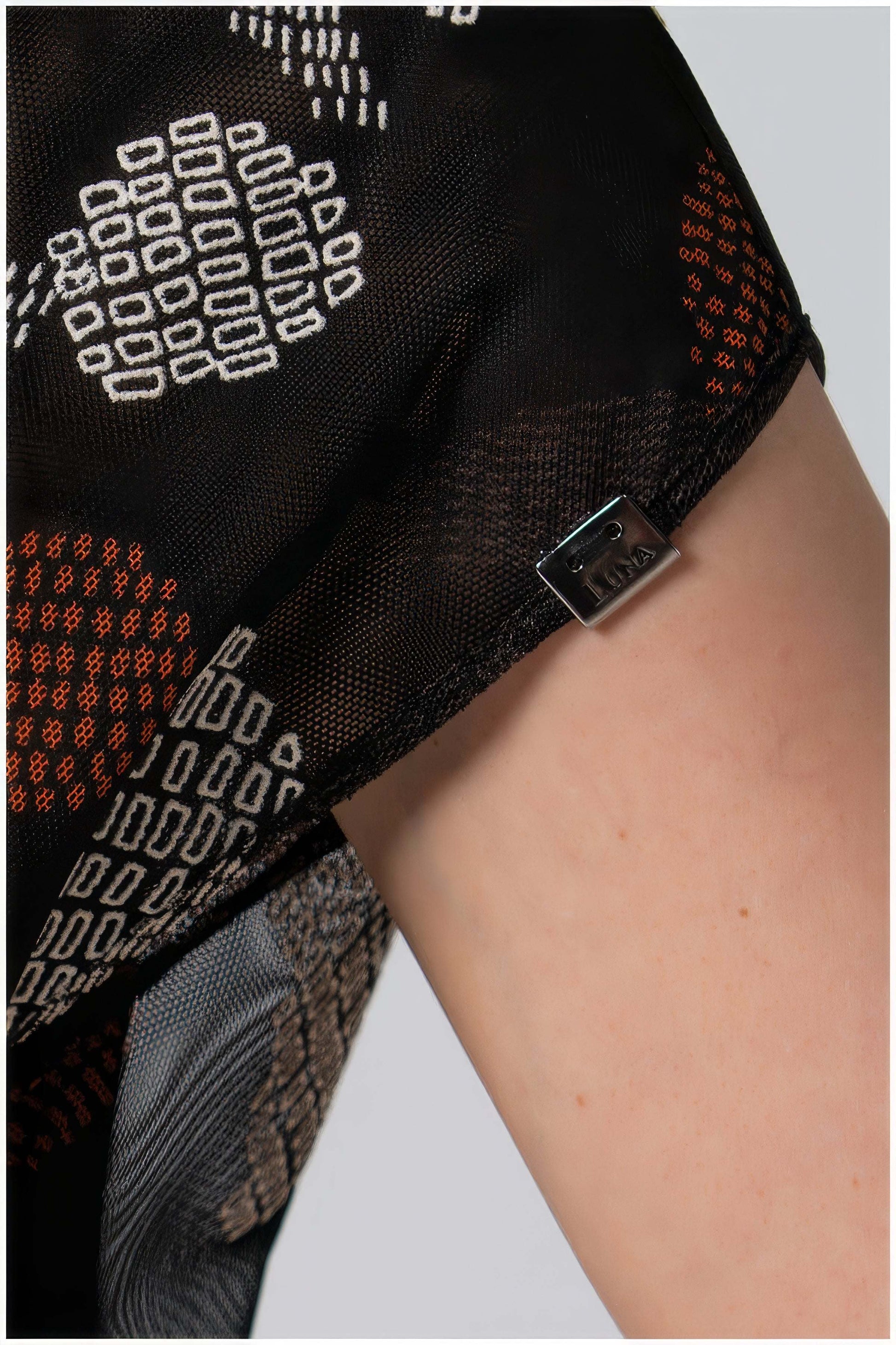 Close-up of a black patterned garment with a belt on a light gray background