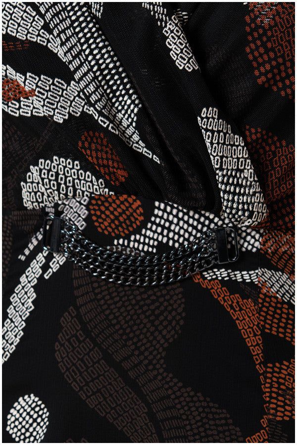 Close-up of black dress fabric with white and rust geometric patterns and decorative chain detail on Long Dress Lola.
