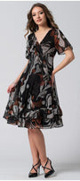 Woman wearing a flowing wide dress black and brown patterned Short Dress Lola with deep V-neck and soft flounces, styled with black heels.