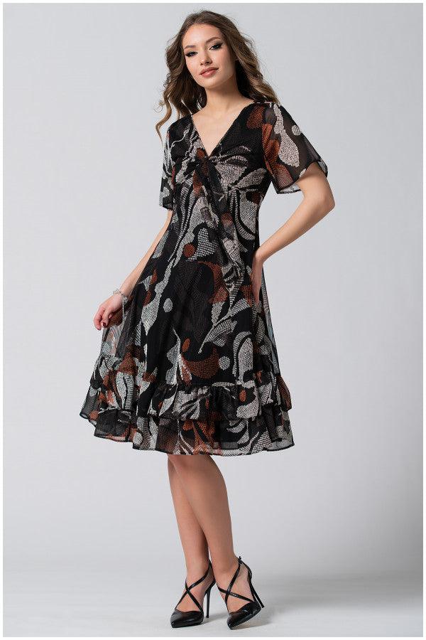 Woman wearing a flowing wide dress black and brown patterned Short Dress Lola with deep V-neck and soft flounces, styled with black heels.