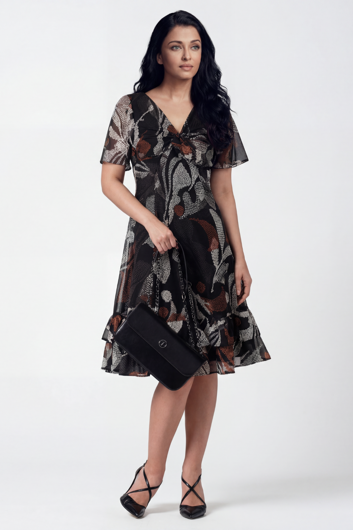 Woman wearing a patterned dress holding a clutch against a white background