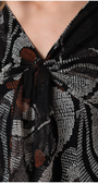 Close-up of a patterned scarf with a knot, featuring black, white, and orange colors.