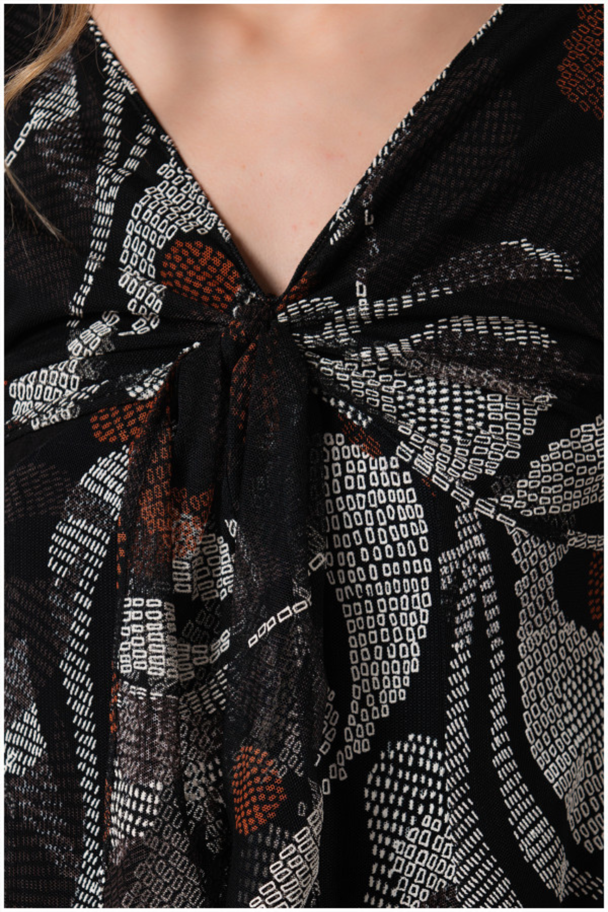 Close-up of a patterned scarf with a knot, featuring black, white, and orange colors.